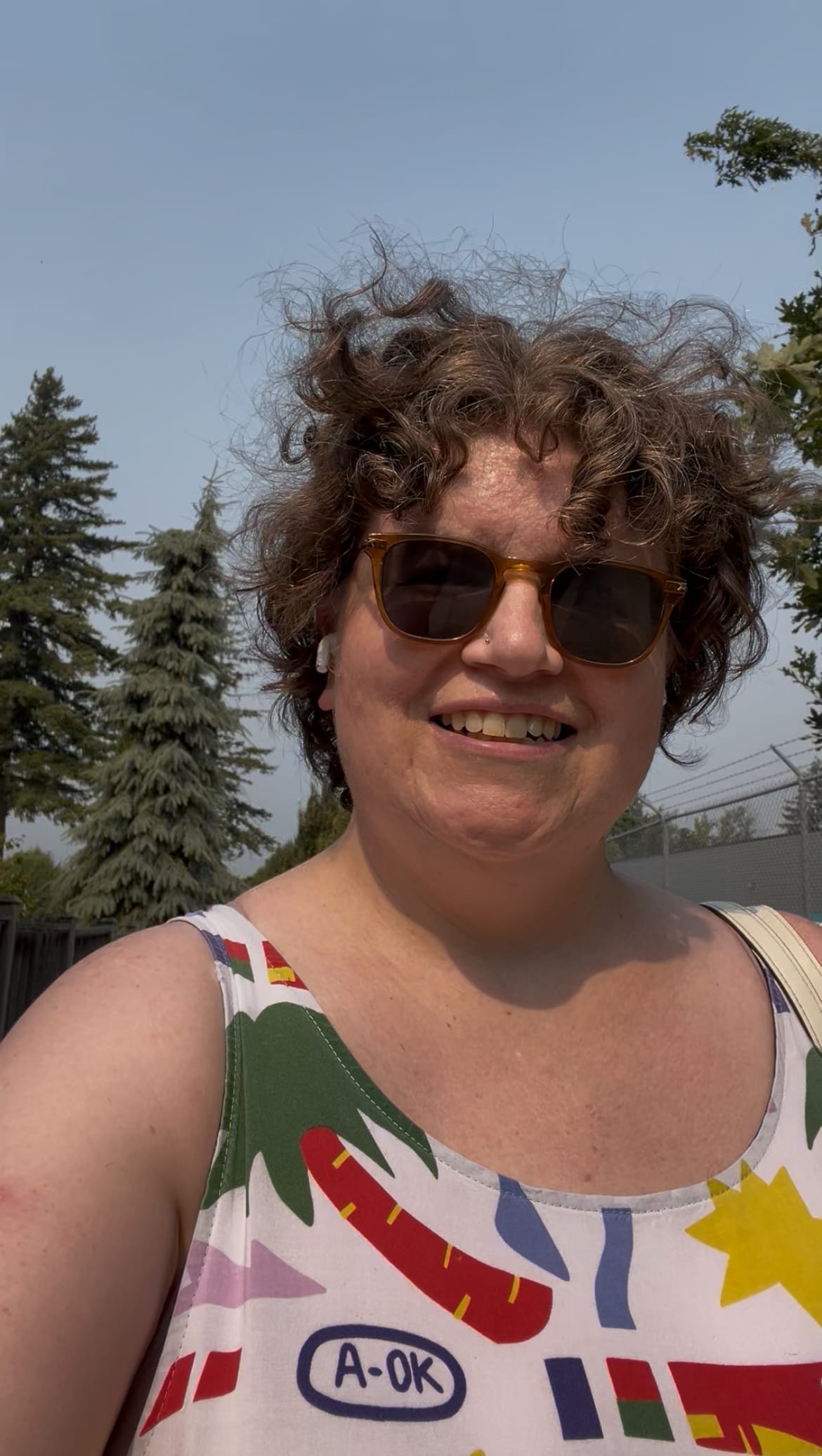curly haired white woman wearing a sundress and sunglasses